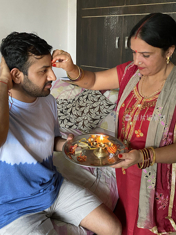 印度的兄弟姐妹参加Raksha Bandhan印度教节日的兄弟和爱的形象，thali(盘)米粒，sindoor(红色粉末)，rakhi(手镯)，Kaju kati(腰果软糖糖果)，Diya(灯)，聚焦前景